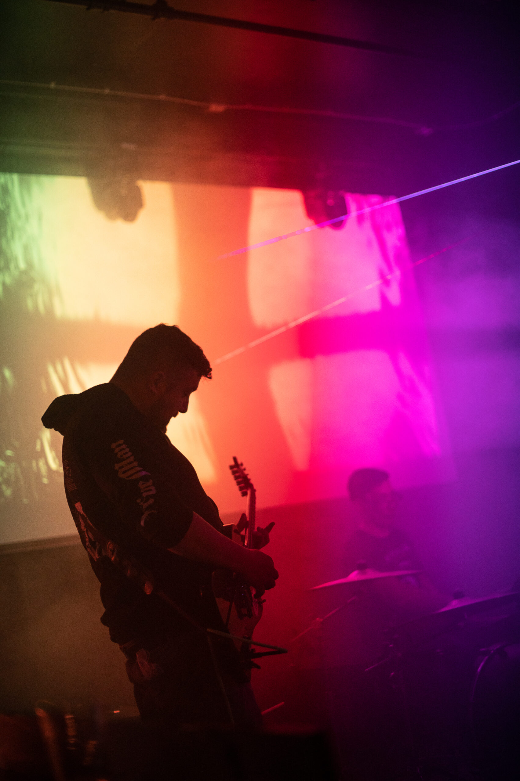 Silhouette of a guitarist performing on stage with colorful lights in the background.